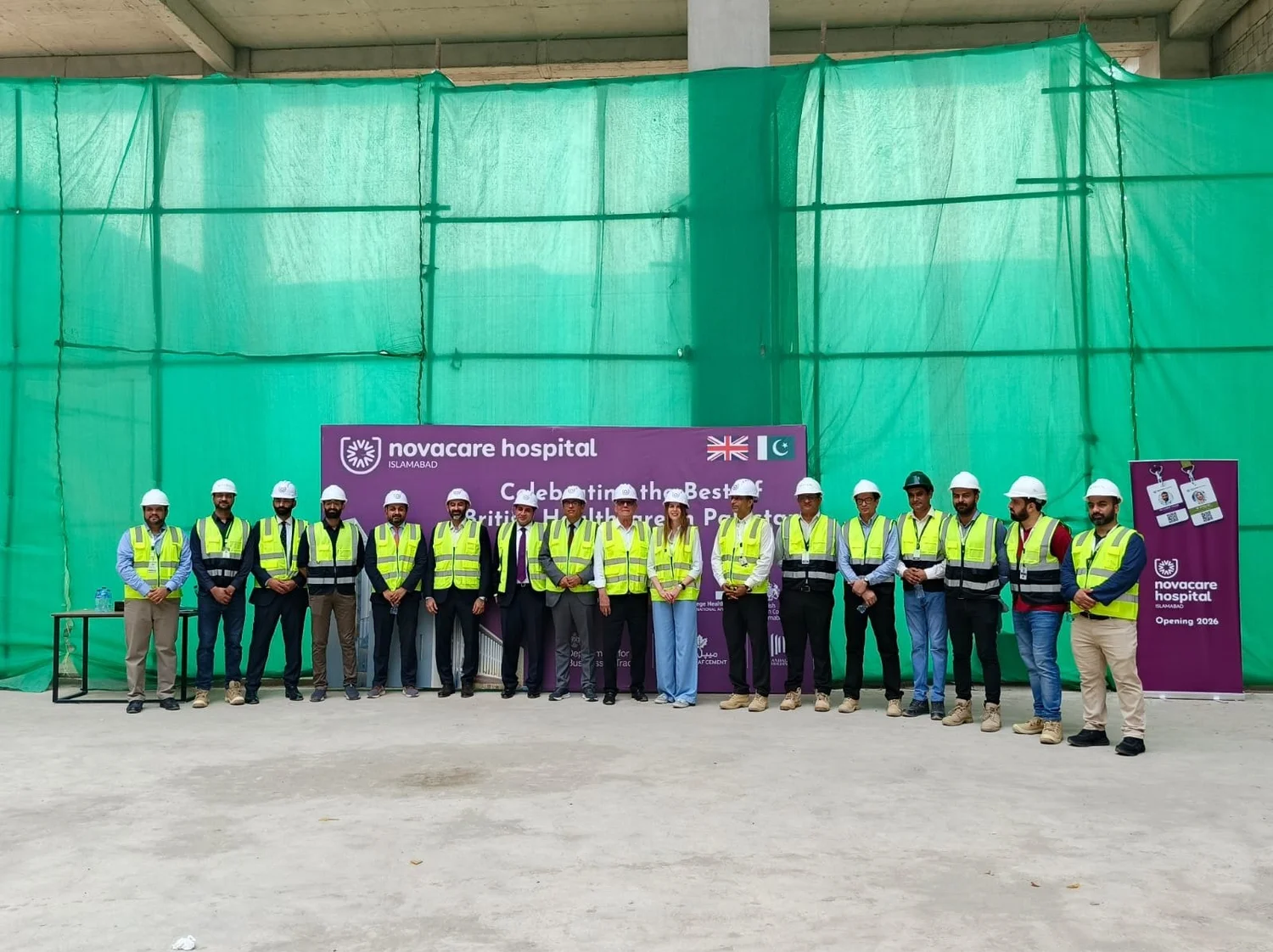 The British delegation and the Novacare team in safety vests and helmets on the hospital construction site